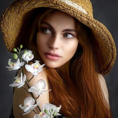 Red-haired woman with hat, posing with flowers