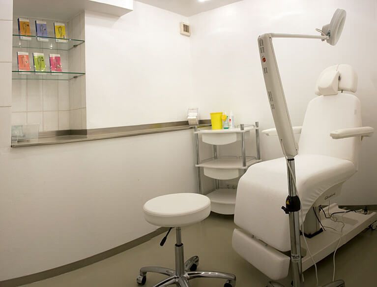 Behandlungszimmer in weiß. Patientenstuhl mit Arztstuhl, Equipment und Möbel.