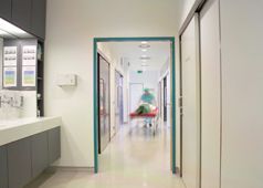 Mitarbeiter schiebt einen Patienten auf einem Klinikbett durch den Gang der Praxis.