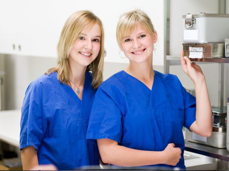 Zwei junge Klinikmitarbeiterin lächeln in die Kamera.