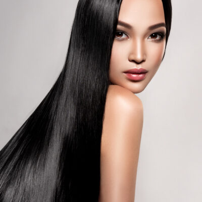 Black haired young woman with asian appearance is demonstrating dense, well cared, straight hair and vivid evening makeup on the face.Asian beauty. Hairdressing art, hair care and beauty products.