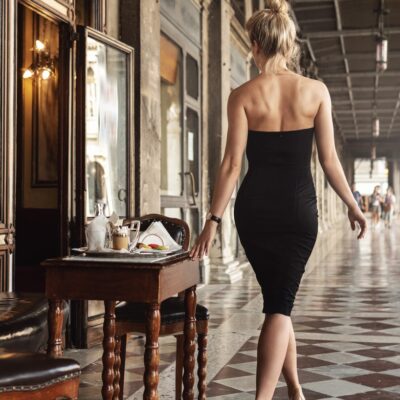 Eine Frau in eleganten Abendkleid läuft einen Flur entlang.