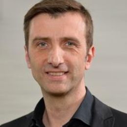 Headshot von Dr. med. Johannes Schmitt lächelnd. Aufgenommen vor einem hellen Hintergrund.