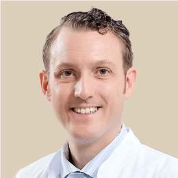 Headshot von Dr. Manuel Hrabowski lächelnd. Aufgenommen vor einem hellen Hintergrund.