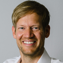 Headshot von Dr. med. Gunnar Hübner lächelnd. Aufgenommen vor einem hellen Hintergrund.