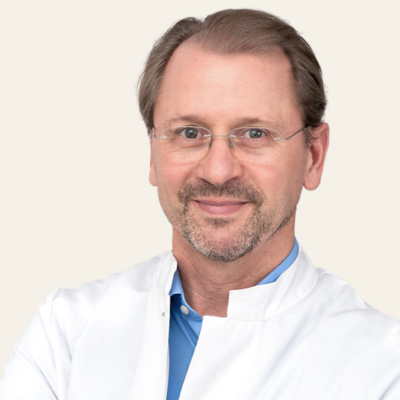 Porträt-Foto von Dr. med. Martin Reifenrath lächelnd. Aufgenommen vor einem hellen Hintergrund.