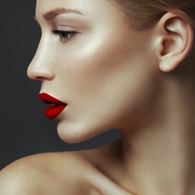 Seitenprofil einer jungen Frau. Sie trägt roten Lippenstift.
