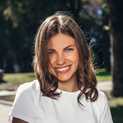 Portrait of a young cute girl in a white T-shirt with a smile in the park. Attractive girl smiling in the park and looking at the camera