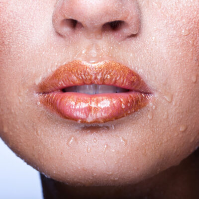 Frau mit Feuchtigkeit im Gesicht und auf den Lippen hat viel Wasser nach einer Hyaluron Behandlung getrunken.