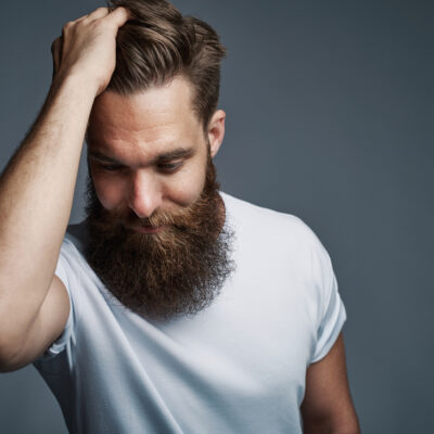 Mann fasst sich ins ein volles haar nach einer Haartransplantation mit Eigenhaar.