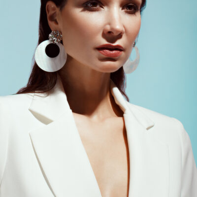 Frau mit großen Ohringen benötigt Earlobe Repair Ohrenkorrektur.